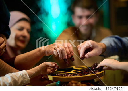 In this modern portrayal, a European Islamic family partakes in the tradition of breaking their Ramadan fast with dates, symbolizing unity, cultural heritage, and spiritual observance during the holy In this modern portrayal, a European Islamic family partakes in the tradition of breaking their Ramadan fast with dates, symbolizing unity, cultural heritage, and spiritual observance during the holy 112474934
