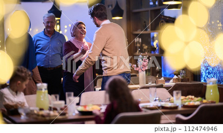 Grandparents arrive at their children's and grandchildren's gathering for iftar in a restaurant during the holy month of Ramadan, bearing gifts and sharing cherished moments of love, unity, and 112474946