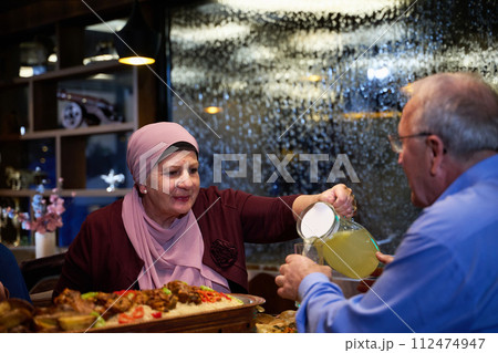 In a modern restaurant setting, an elderly Islamic European couple shares a meal for iftar during the holy month of Ramadan, epitomizing unity, companionship, and cultural tradition in their dining 112474947