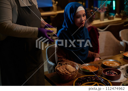 In a heartwarming scene, a professional chef serves an European Muslim family their iftar meal during the holy month of Ramadan, embodying cultural unity and culinary hospitality in a moment of shared 112474962