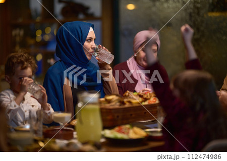 A modern and traditional European Islamic family comes together for iftar in a contemporary restaurant during the Ramadan fasting period, embodying cultural harmony and familial unity amidst a 112474986