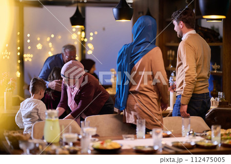Grandparents arrive at their children's and grandchildren's gathering for iftar in a restaurant during the holy month of Ramadan, bearing gifts and sharing cherished moments of love, unity, and 112475005