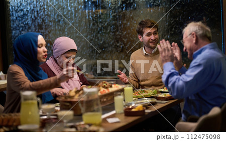 A modern and traditional European Islamic family comes together for iftar in a contemporary restaurant during the Ramadan fasting period, embodying cultural harmony and familial unity amidst a A modern and traditional European Islamic family comes together for iftar in a contemporary restaurant during the Ramadan fasting period, embodying cultural harmony and familial unity amidst a 112475098