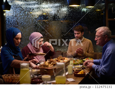 A modern and traditional European Islamic family comes together for iftar in a contemporary restaurant during the Ramadan fasting period, embodying cultural harmony and familial unity amidst a A modern and traditional European Islamic family comes together for iftar in a contemporary restaurant during the Ramadan fasting period, embodying cultural harmony and familial unity amidst a 112475131