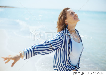 smiling modern female on beach rejoicing 112475507