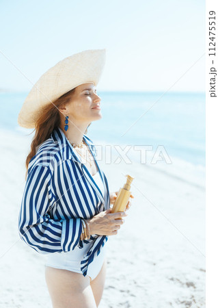 smiling stylish woman on seacoast with spf smiling stylish woman on seacoast with spf 112475519