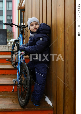 European boy dressed in winter clothes took his bike outside European boy dressed in winter clothes took his bike outside 112475535