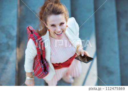 Upper view of smiling woman in dress and jacket in city 112475869