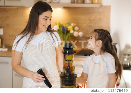 Mom and daughter making homemade healthy juice. Organic fruits and vegetables. Vegan beverage Mom and daughter making homemade healthy juice. Organic fruits and vegetables. Vegan beverage 112476459
