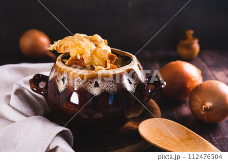 French onion soup with melted cheese and croutons in a pot on the table French onion soup with melted cheese and croutons in a pot on the table 112476504