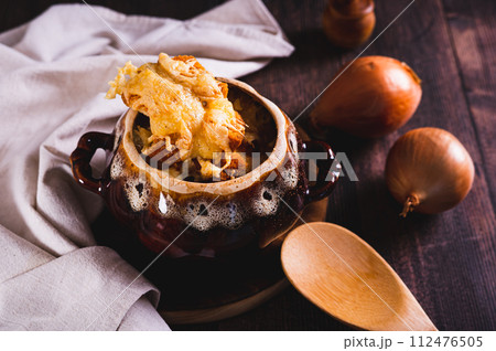 Homemade onion soup with cheese croutons in a pot on the table Homemade onion soup with cheese croutons in a pot on the table 112476505