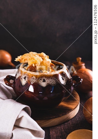 French onion soup with melted cheese and croutons in a pot on the table vertical view 112476506