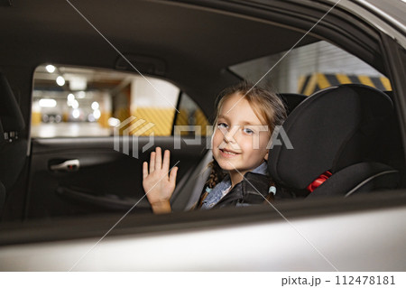 Caucasian little girl sitting on back seat of modern car in child chair. Caucasian little girl sitting on back seat of modern car in child chair. 112478181
