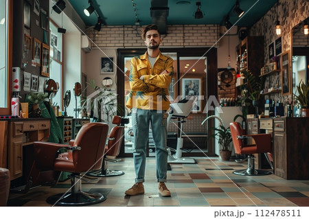 A man stands in a barbershop with a yellow shirt on 112478511