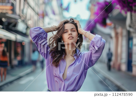 A woman in a purple shirt is standing on a street 112478590