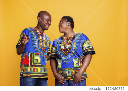 Happy black man and woman couple dancing and making moves together. Smiling wife and husband looking at each other with cheerful and romantic expression and posing in studio 112480881
