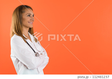 Portrait of a smiling female doctor or nurse wearing white scrubs uniform and stethoscope 112481237