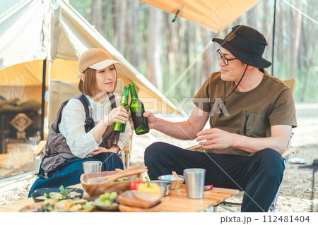 キャンプ場でお酒を飲む夫婦・カップルキャンパー(ビール・キャンプ飯・ご飯) キャンプ場でお酒を飲む夫婦・カップルキャンパー(ビール・キャンプ飯・ご飯) 112481404