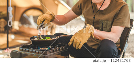 キャンプ場でスキレットを使ってアヒージョを作る男性キャンパー(キャンプ飯) キャンプ場でスキレットを使ってアヒージョを作る男性キャンパー(キャンプ飯) 112481768