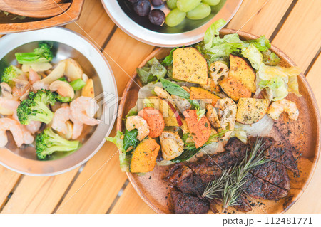 木のテーブルに置かれたキャンプ飯・キャンプ場で食べるご飯・ランチ 112481771