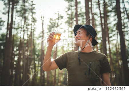 キャンプ場でビールを飲む男性キャンパー（お酒・アルコール・クラフトビール・発泡酒） 112482565