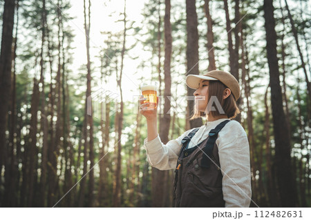 キャンプ場でビールを飲む女性キャンパー（お酒・アルコール・クラフトビール・発泡酒） 112482631