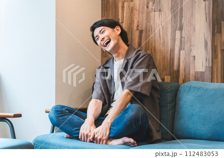 家のリビングでテレビ・動画・映像を見て爆笑する若いアジア人・日本人男性(リラックス) 家のリビングでテレビ・動画・映像を見て爆笑する若いアジア人・日本人男性(リラックス) 112483053