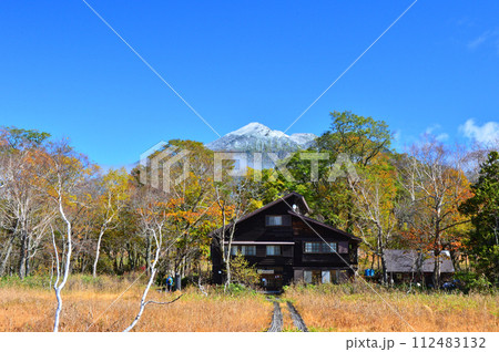 紅葉の尾瀬ケ原に佇む竜宮小屋と新雪の燧ケ岳 112483132
