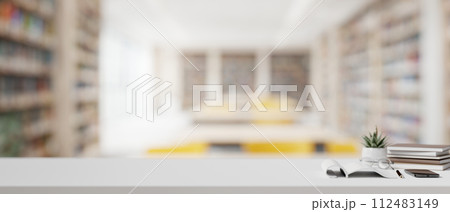 A table features a copy space for display products over a blurred background of a modern library. 112483149
