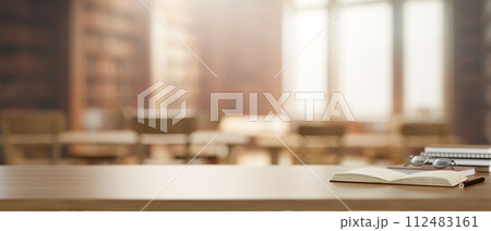 A wooden table features books, eyeglasses, and a presentation space in a library. 112483161