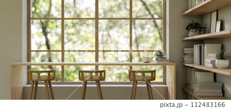 A contemporary neutral lounge features a long wooden table against the window and stools. A contemporary neutral lounge features a long wooden table against the window and stools. 112483166