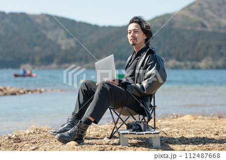 湖でリモートワークをする30代の男性 112487668