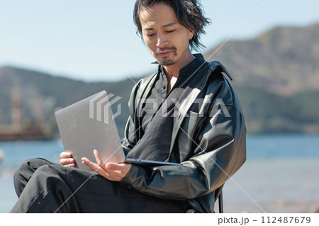 湖でリモートワークをする30代の男性 112487679