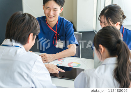 医局でカンファレンス・打ち合わせ・ミーティングする男女の看護師・技師・作業療法士・理学療法士・医師 112488095