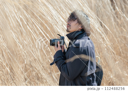 ススキの前でカメラを持つ30代男性 112488256