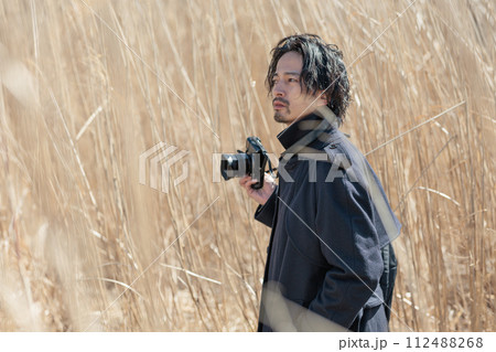 ススキの前でカメラを持つ30代男性 112488268