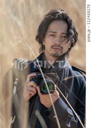 ススキの前でカメラを持つ30代男性 112488278