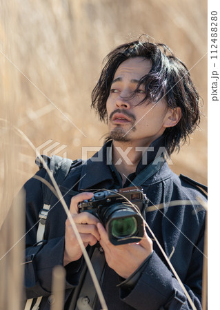ススキの前でカメラを持つ30代男性 112488280