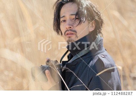 ススキの前でカメラを持つ30代男性 112488287