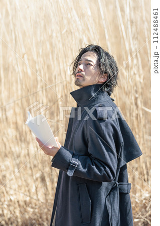 ススキの前で本を持つ30代男性 112488461