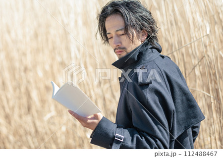 ススキの前で本を持つ30代男性 ススキの前で本を持つ30代男性 112488467