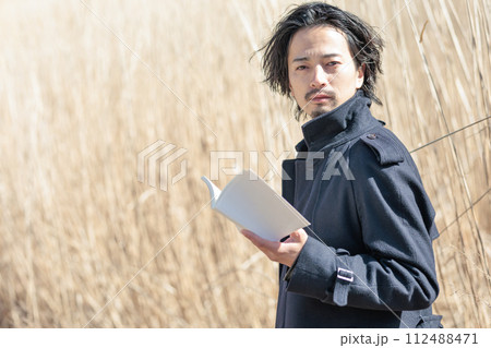 ススキの前で本を持つ30代男性 ススキの前で本を持つ30代男性 112488471