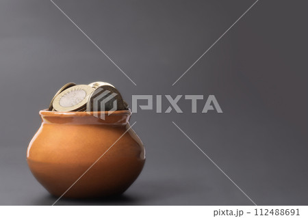 Coins in a clay pot on a gray background with copy space. 112488691