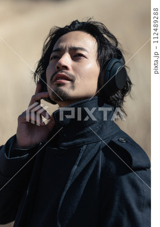 草原の中で音楽を聴く30代男性 草原の中で音楽を聴く30代男性 112489288