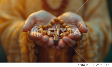 Soulful prayer: a man in quiet devotion, hands clasped around a rosary cross, seeking solace and spiritual connection, capturing the essence of serene contemplation, faith, and religious devotion. 112490847