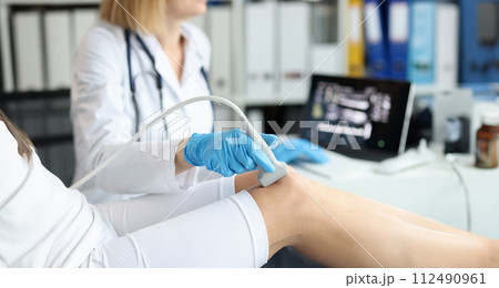 Doctor doing ultrasound examination of patient knee joint in clinic closeup Doctor doing ultrasound examination of patient knee joint in clinic closeup 112490961