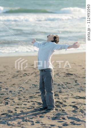 海辺に佇む白シャツを着た30代男性 112491040