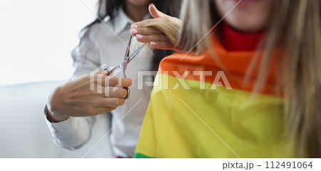 Woman hairdresser cutting ends of client hair with scissors closeup 112491064