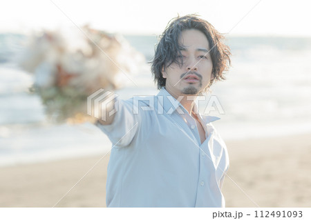 海辺で花束を渡す笑顔の男性|ウェディングやライフスタイル広告に 海辺で花束を渡す笑顔の男性|ウェディングやライフスタイル広告に 112491093