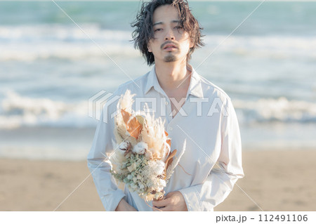 浜辺で花束を持つ男性｜結婚・告白・贈り物シーンに最適 112491106